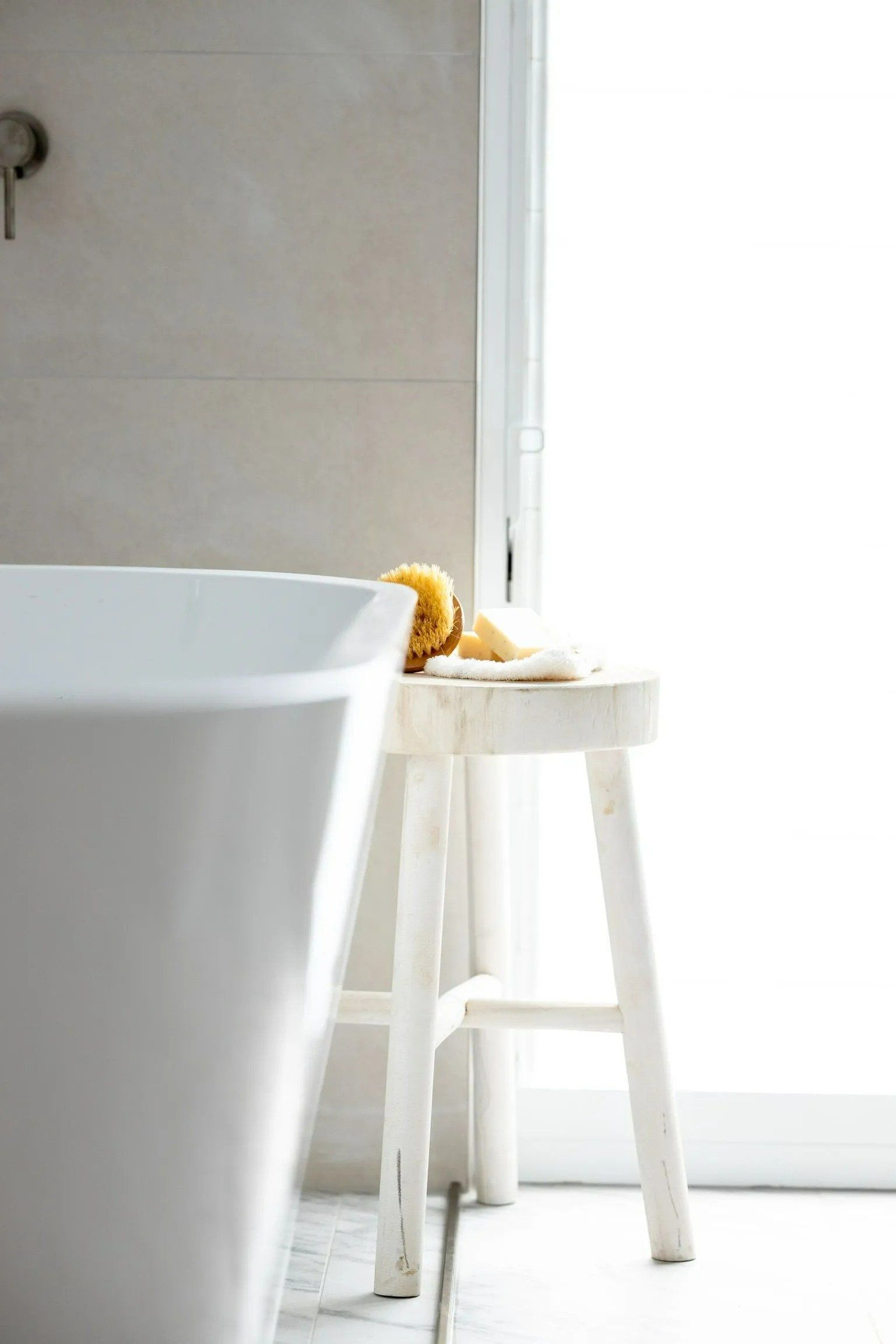 A White Stool Is Sitting Next to A Bathtub in A Bathroom — Blue Horizon Projects in Toowoon Bay, NSW