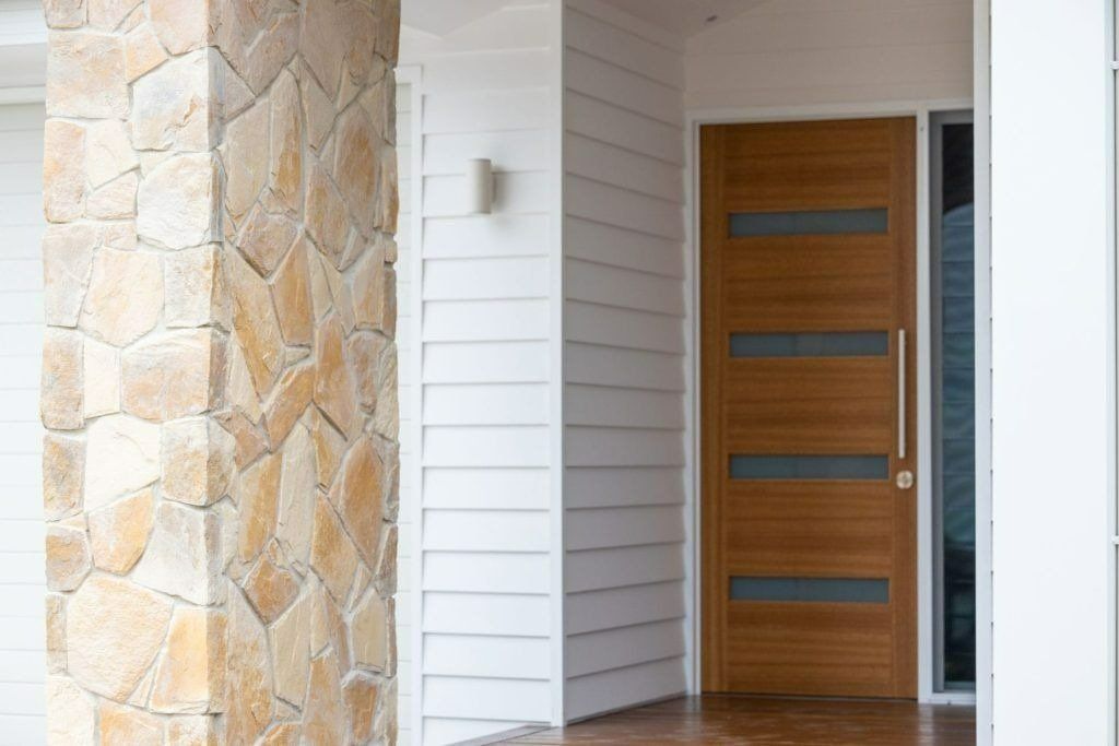 The Front Door of A House with A Stone Wall and A Wooden Door — Blue Horizon Projects in Long Jetty, NSW