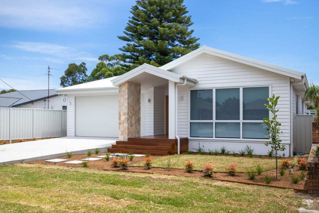 White house with a garage, brown steps, and a small lawn on a sunny day. — Blue Horizon Projects in Bateau Bay, NSW