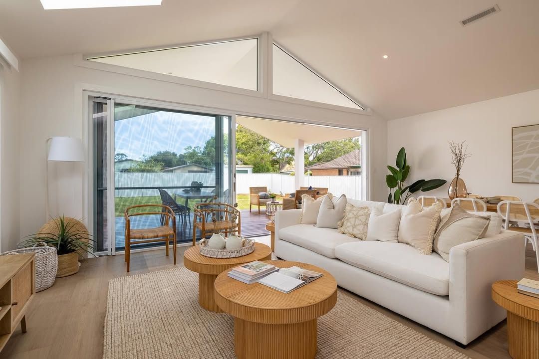A Living room with circle coffee tables and a couch in front of large glass doors — Blue Horizon Projects in Bateau Bay, NSW