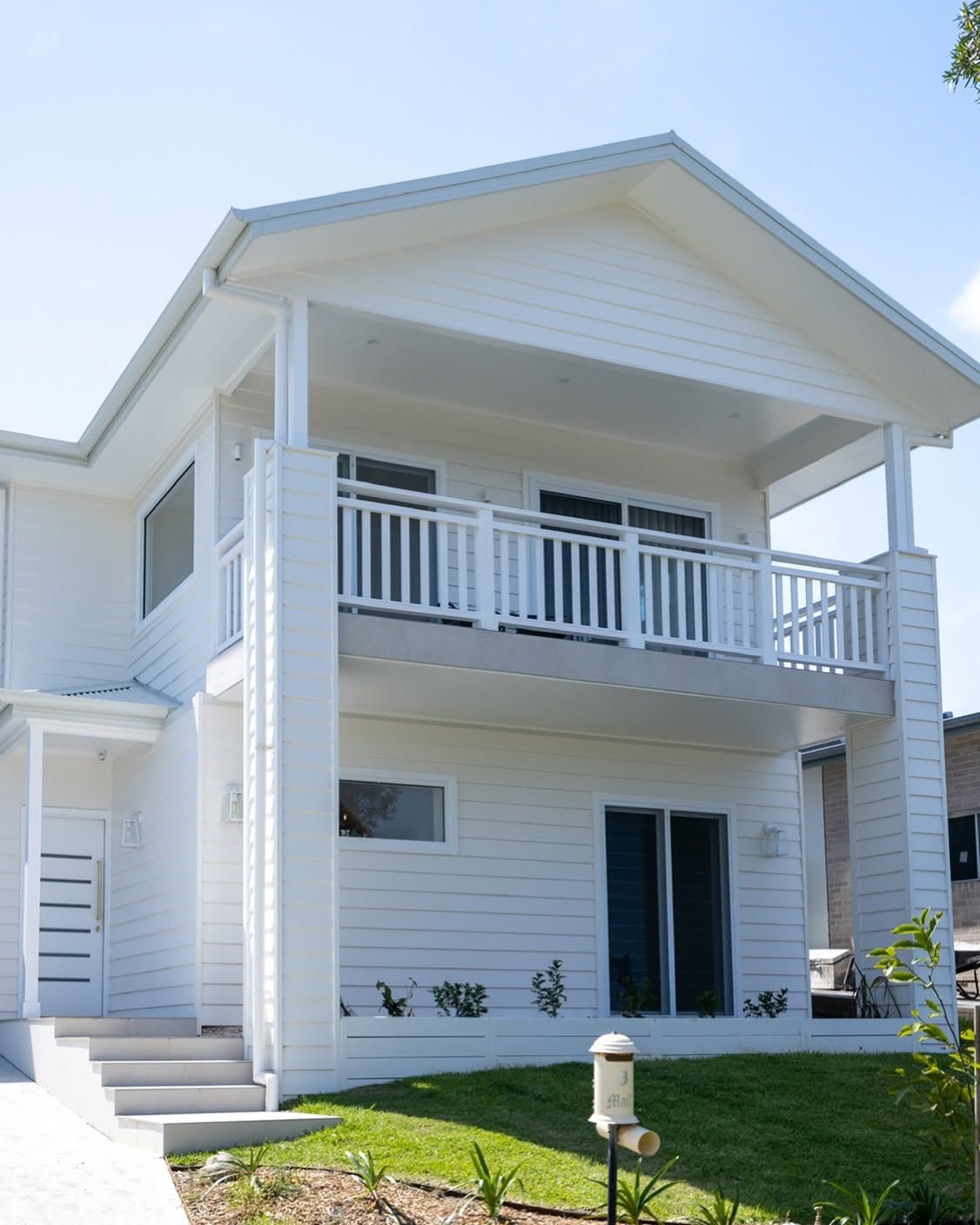 A Large House with A Lot of Windows and A Garage — Blue Horizon Projects in Bateau Bay, NSW