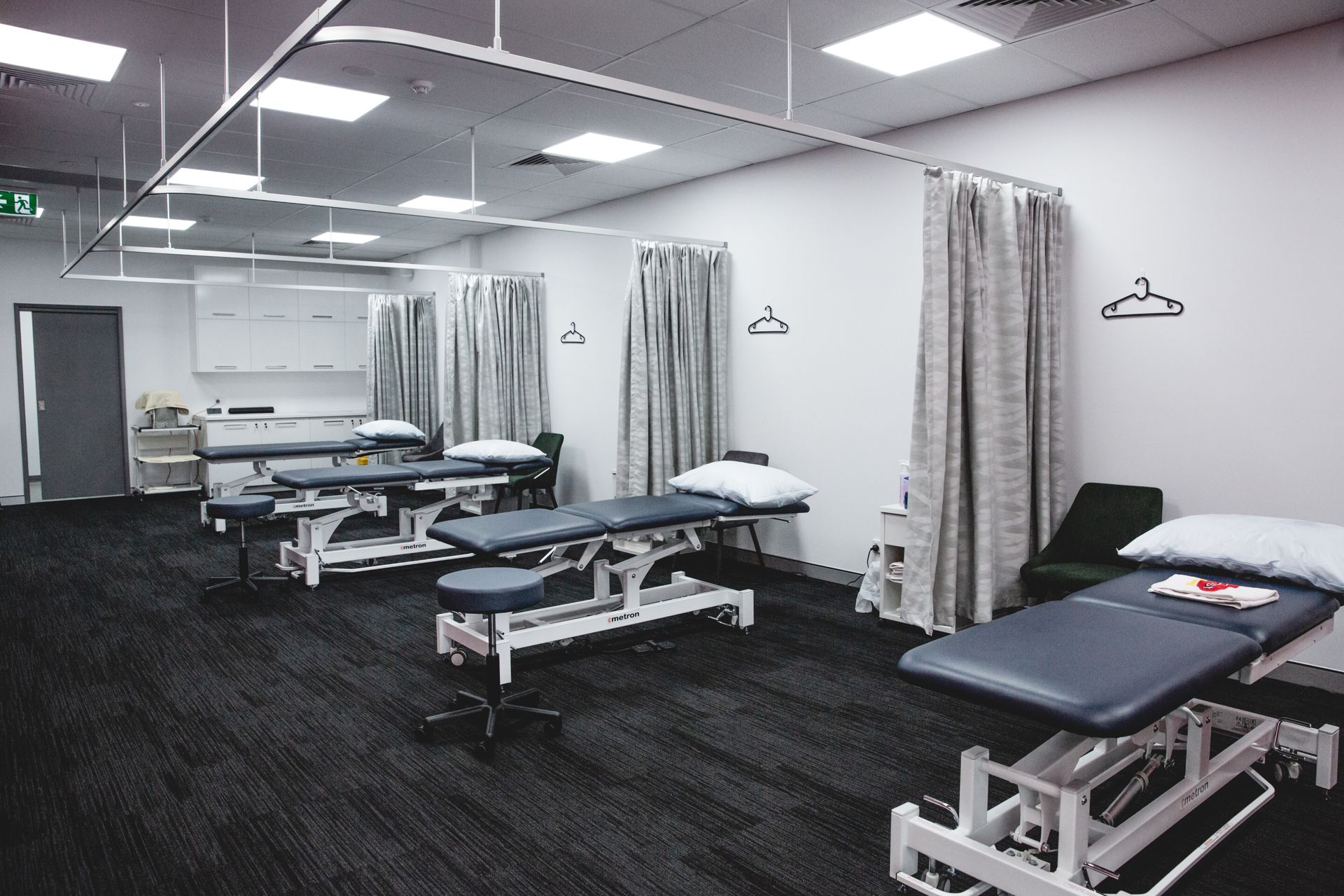 Physiotherapy clinic with treatment tables, curtains, and equipment.