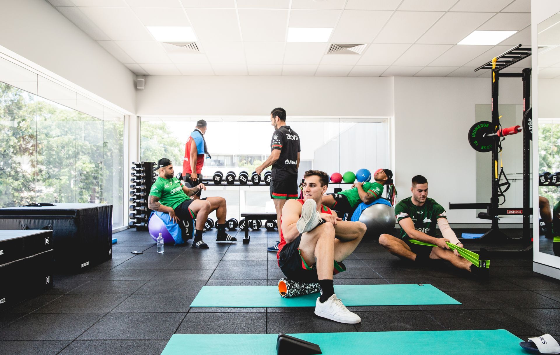 People stretching and exercising in a gym with various equipment.