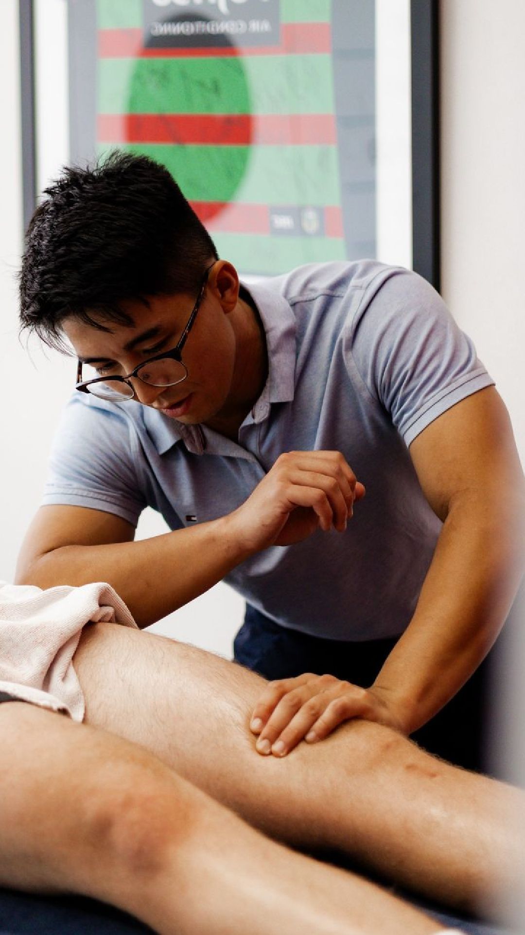 Therapist massaging a person's leg at a clinic, looking focused.