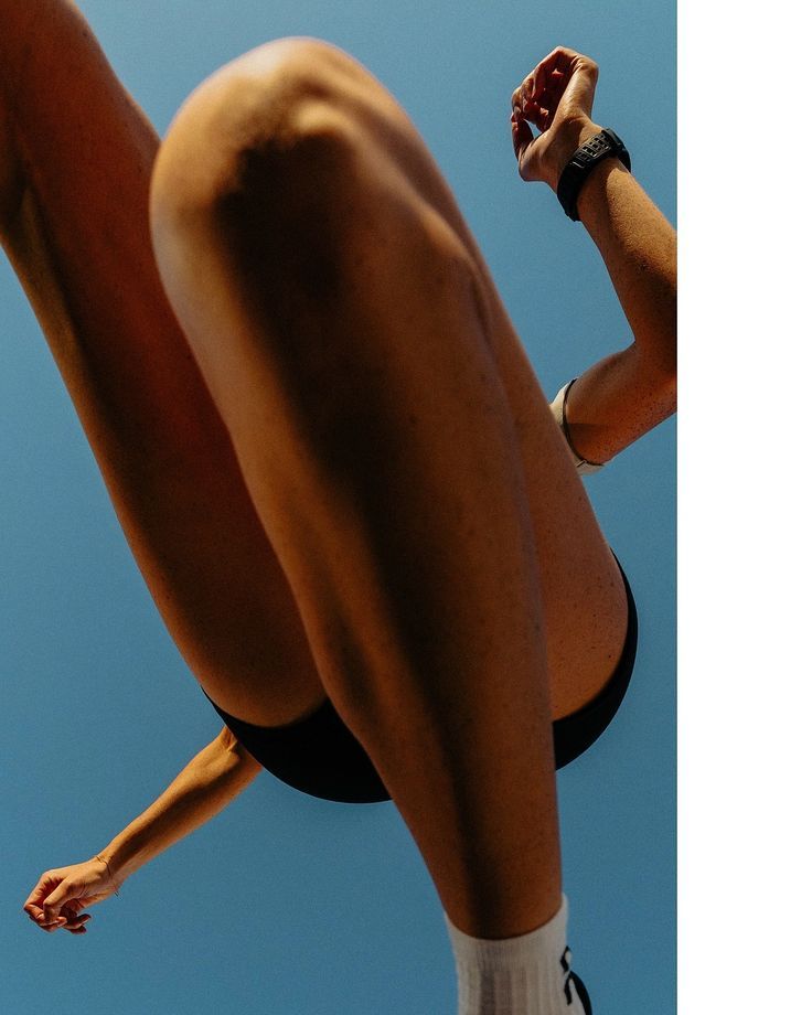 Close-up of a person jumping against a blue sky, wearing black shorts and white socks.