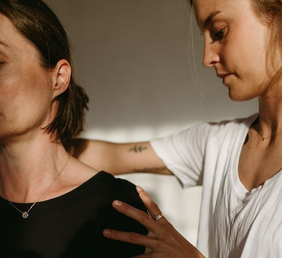 Person in white shirt touching another person’s shoulder