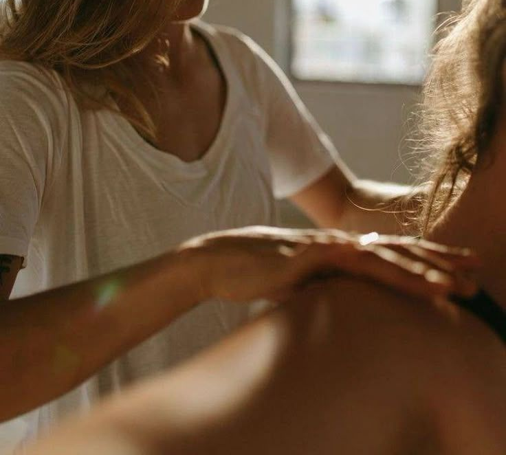 Hands performing a forearm massage on a person lying down, in a soft-lit setting