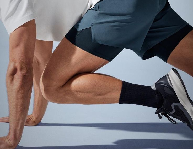 Person holding a black dumbbell while kneeling on a gym floor