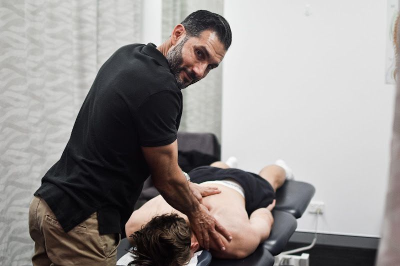 Man giving a massage to a person lying face down on a massage table. Interior setting.