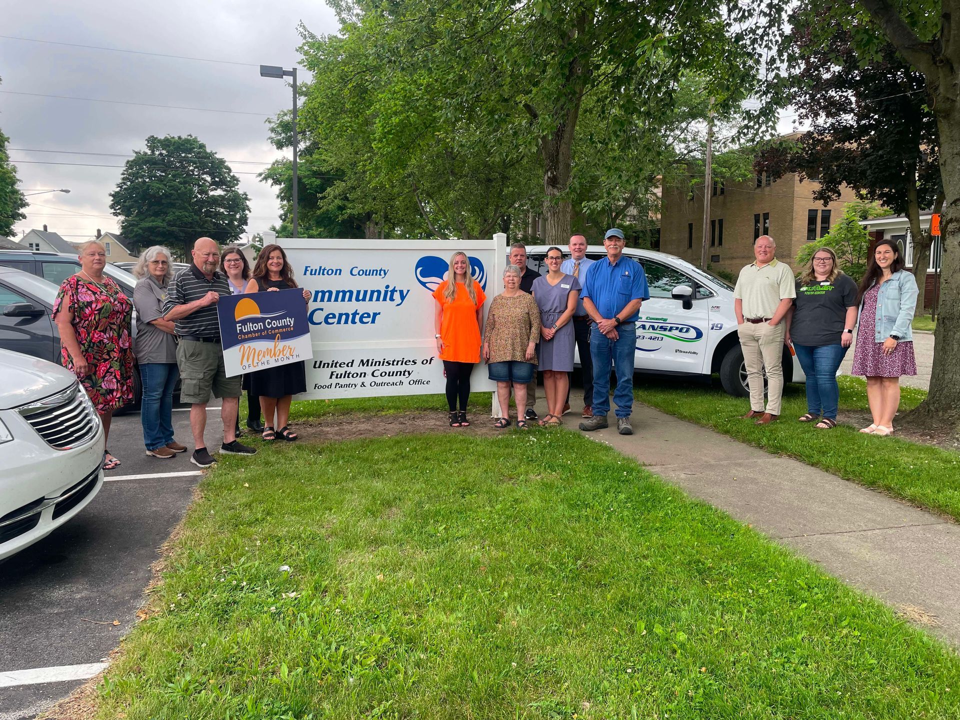 A group of people standing in front of a Pitkin County Community Center sign holding a Sun Way sign in an outdoor setting.