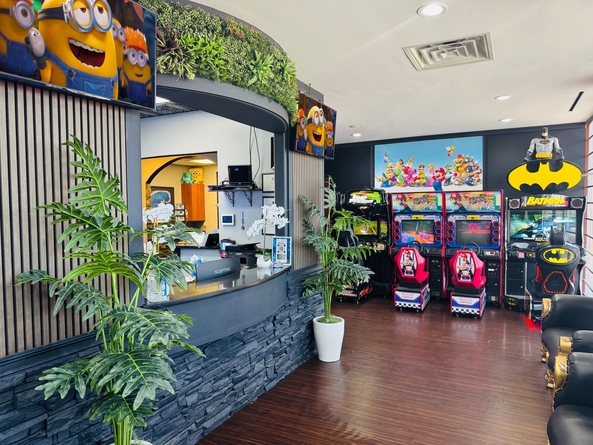 Colorful arcade entrance with claw machines, Minions decor, and a reception counter inside a bright lobby