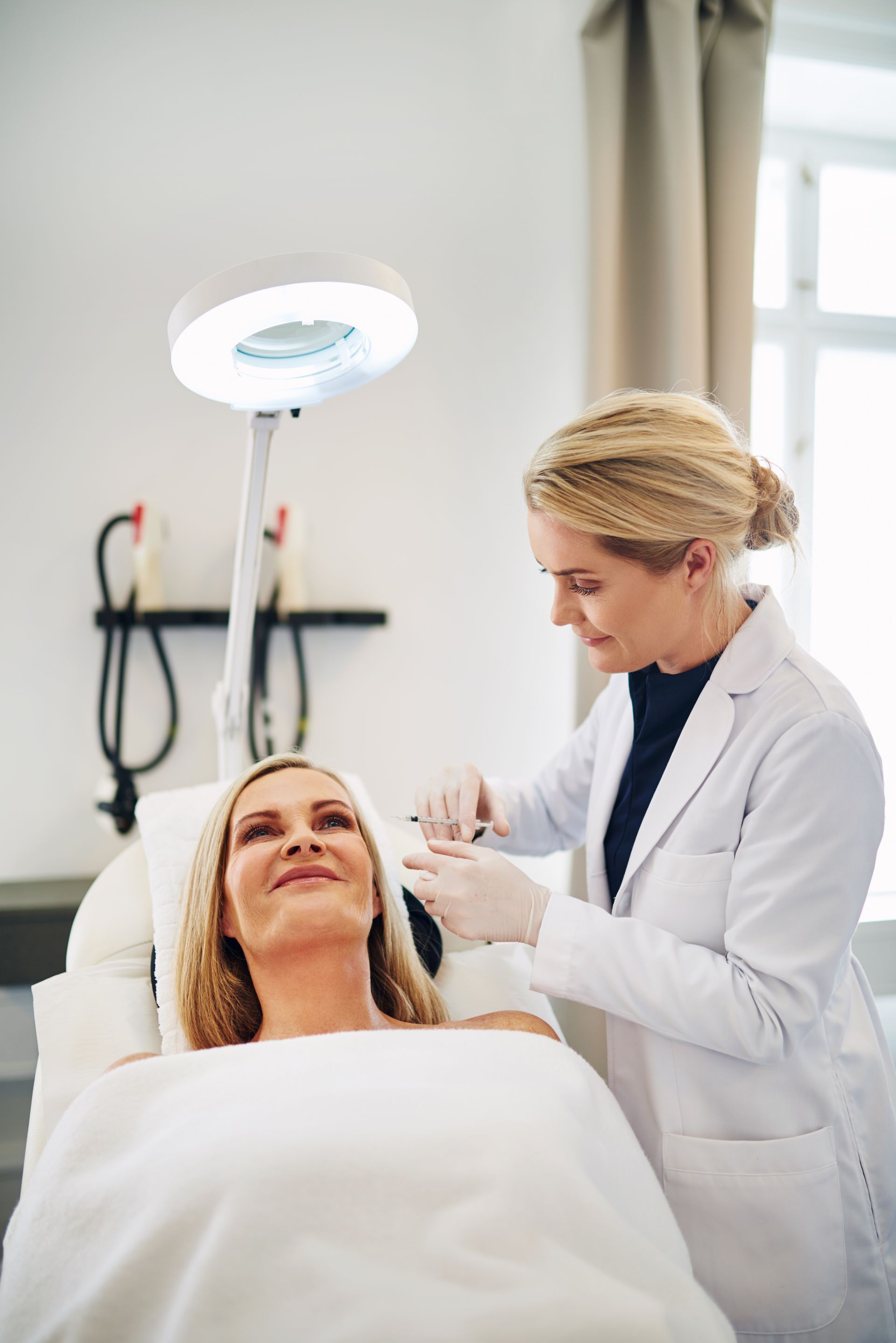 Aesthetician applying treatment to a client in a bright spa room