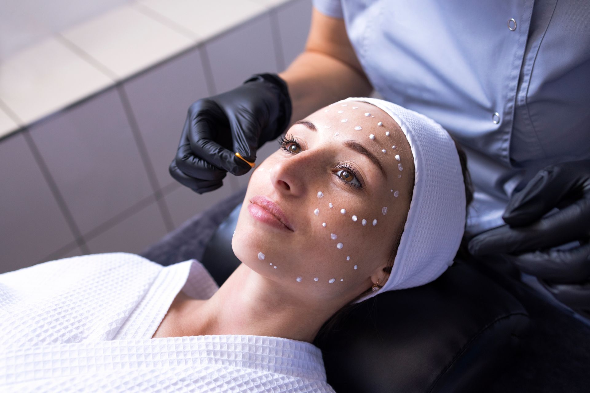 Woman receiving a facial treatment with marked points on her face in a spa clinic