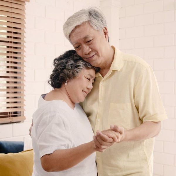 A man and woman are hugging and holding hands in a living room