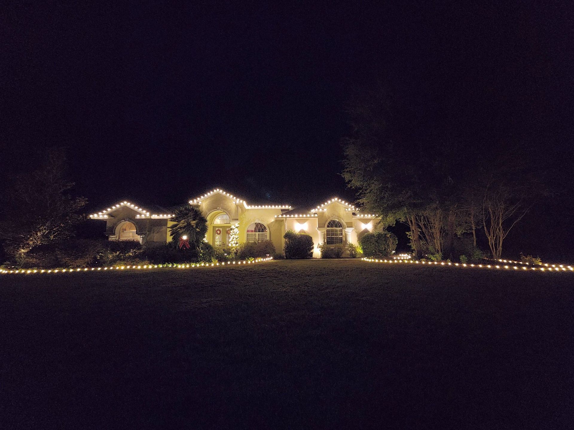 House lit with blue, pink, and purple holiday lights at night