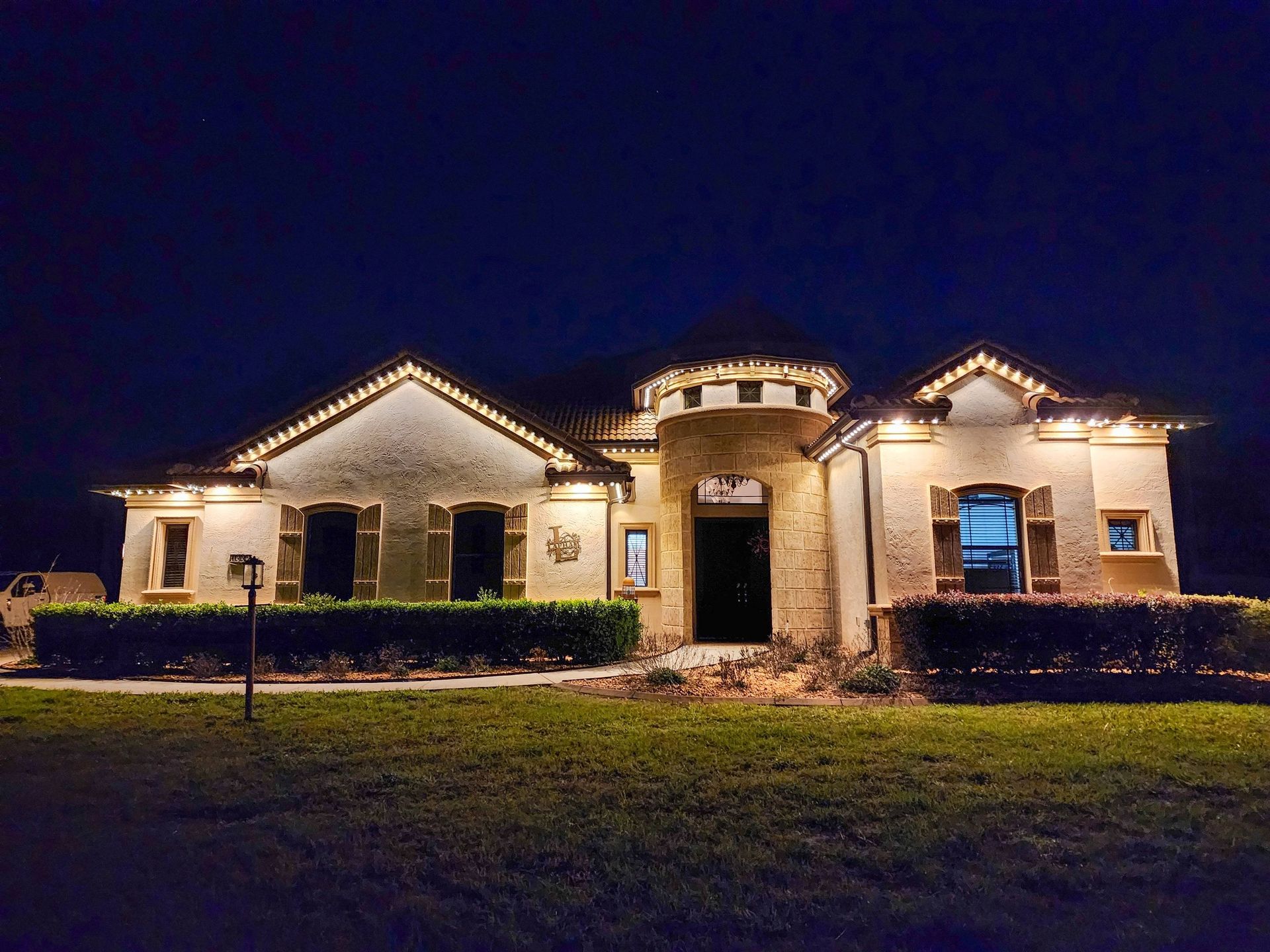 House lit with blue, pink, and purple holiday lights at night