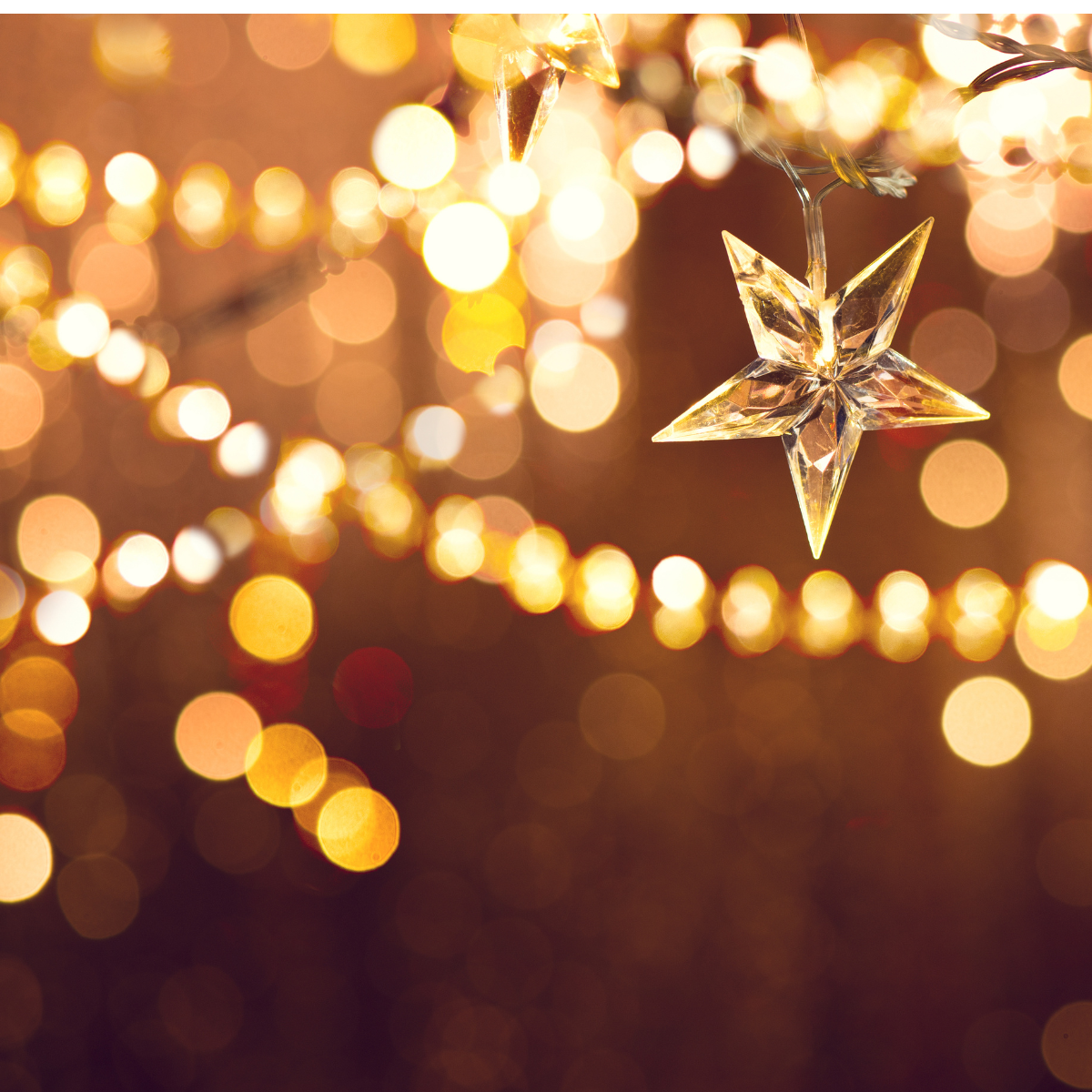 Golden star ornament hanging among warm, blurred holiday lights on a festive background