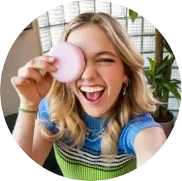 een girl smiling and holding compact near face