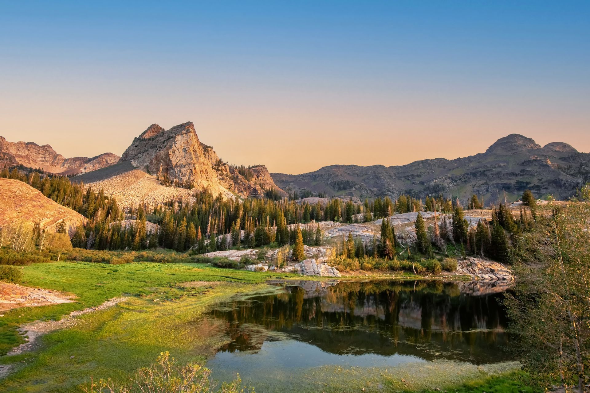 there is a lake in the middle of a field with mountains in the background .