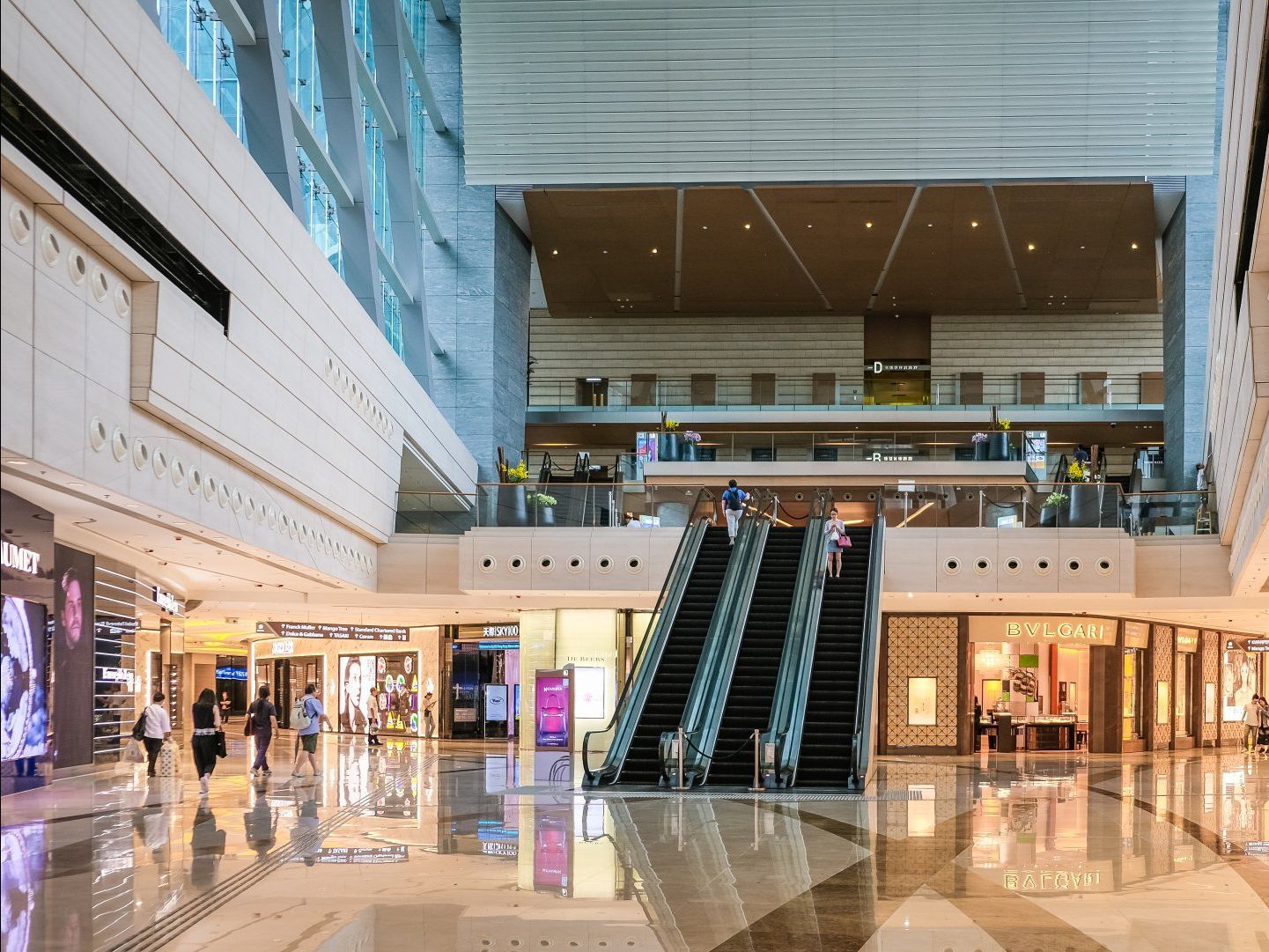 a large shopping mall with escalators going up and down .
