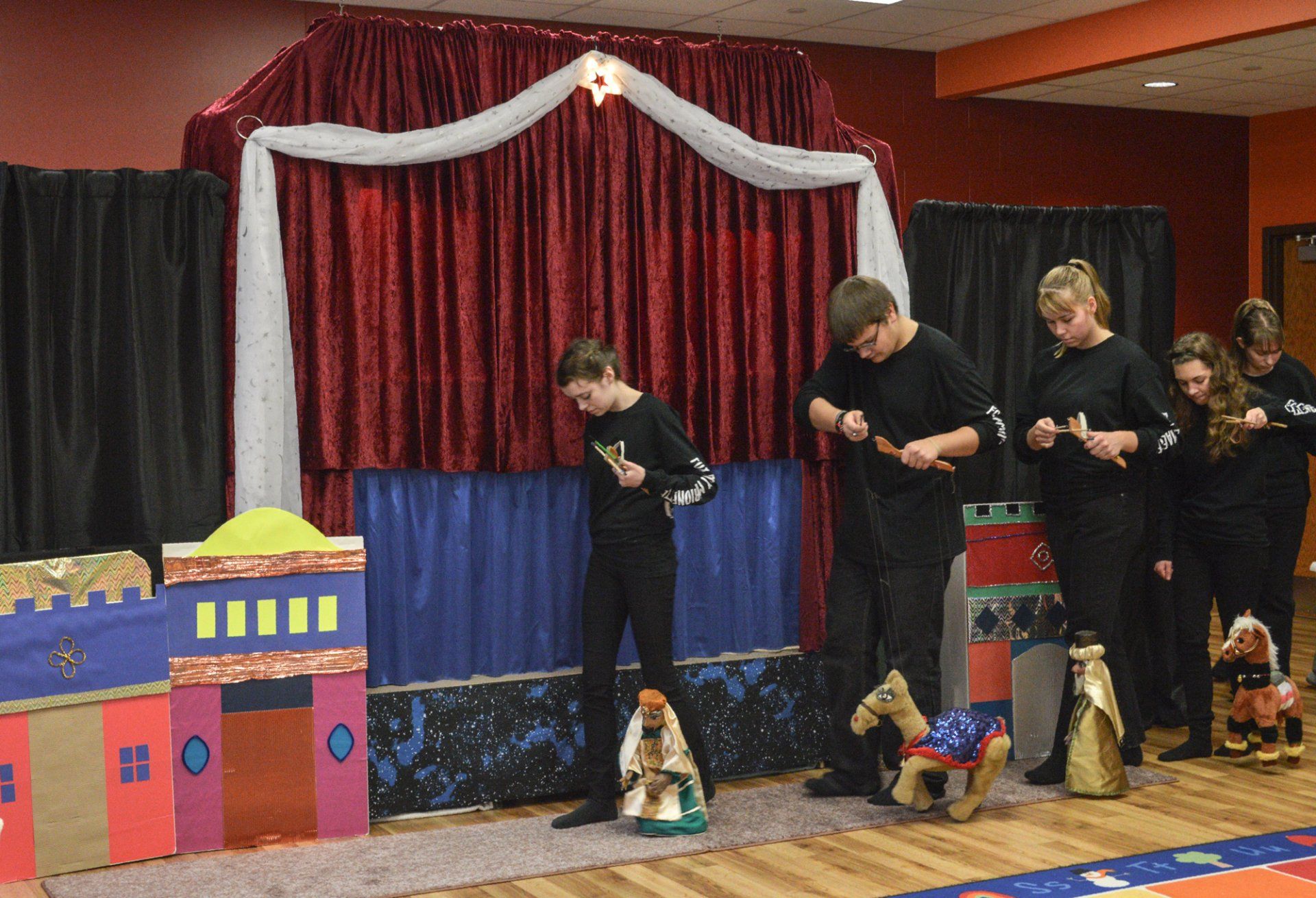 Wise men  and camel marionettes trek in front of the stage