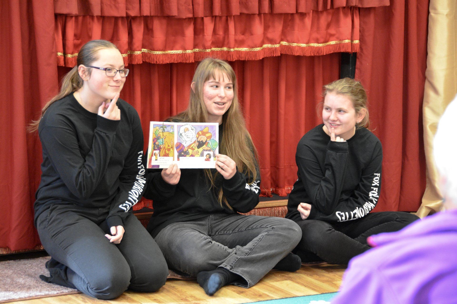 Puppeteers read picture books to the audience before the show