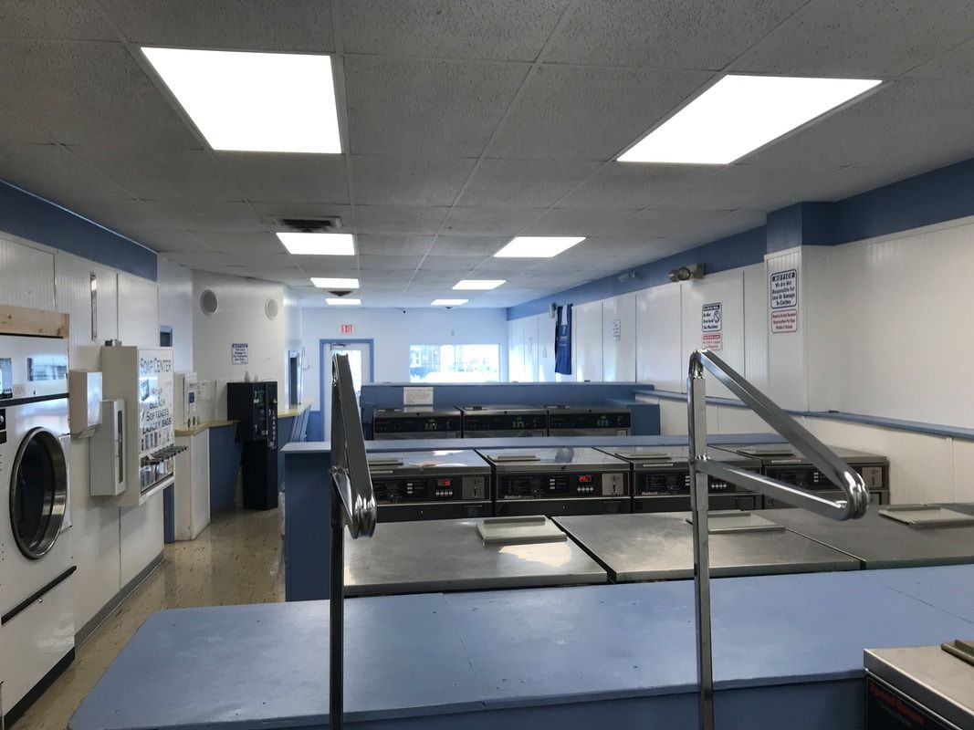 Laundry room with washers, folding tables, and blue walls under fluorescent lights