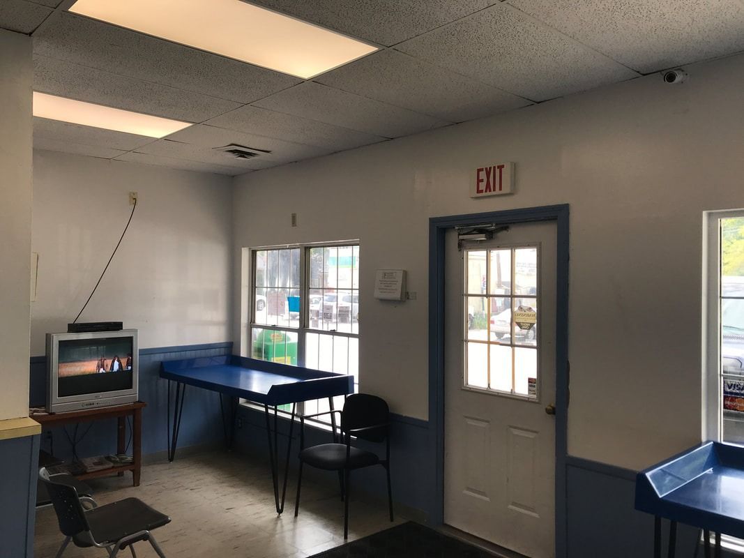 Small room with blue tables, chairs, windows, and a door with an EXIT sign.