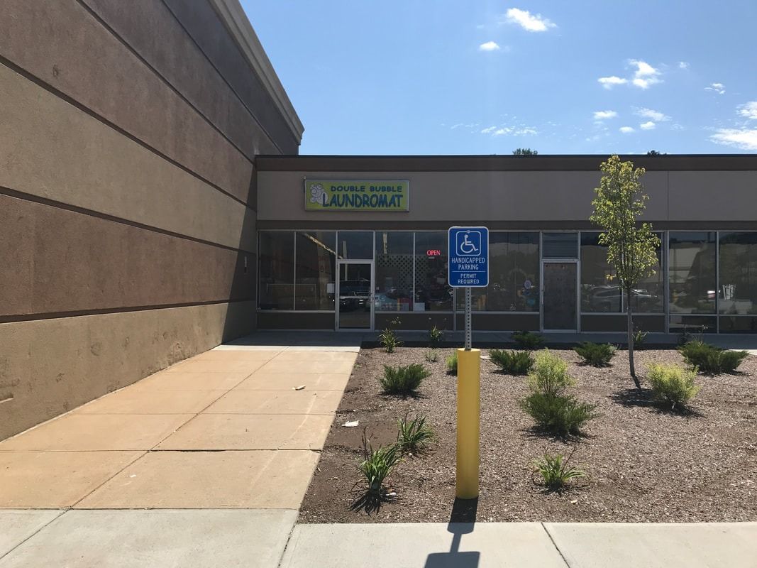 Accessible storefront with handicap parking sign, desert landscaping, and a tan building entrance