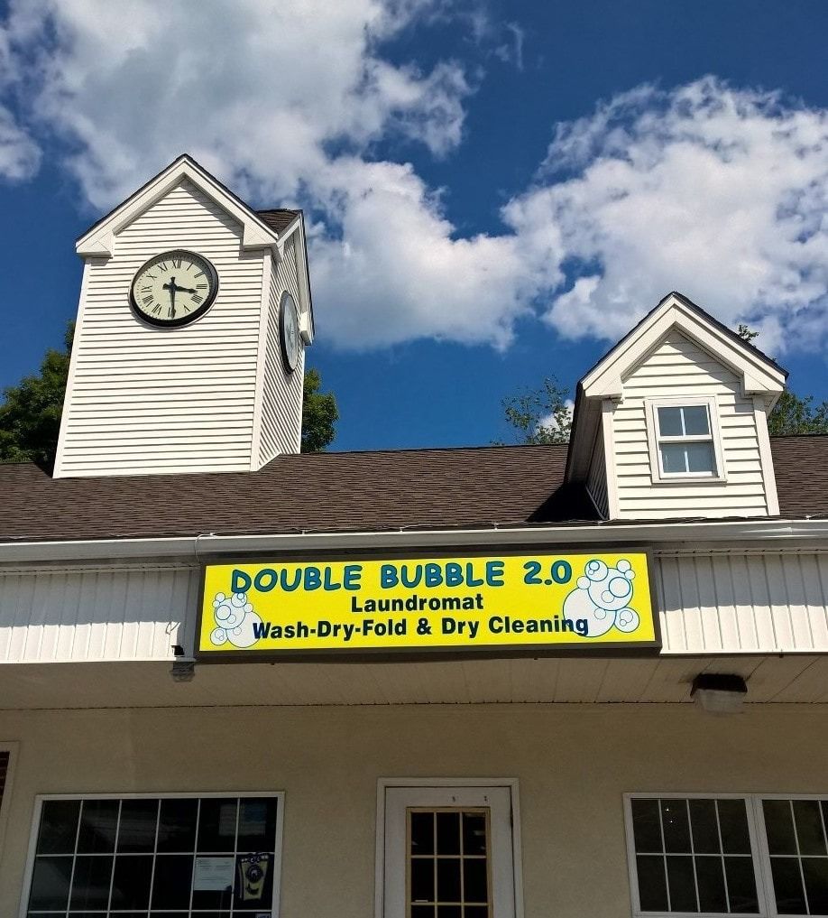 Laundry storefront with yellow Double Bubble sign and two white clock towers under a blue sky