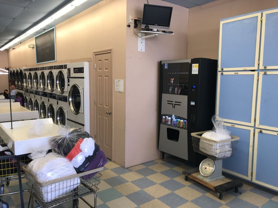 Laundry room with washers, dryers, folding tables, vending machines, and laundry baskets