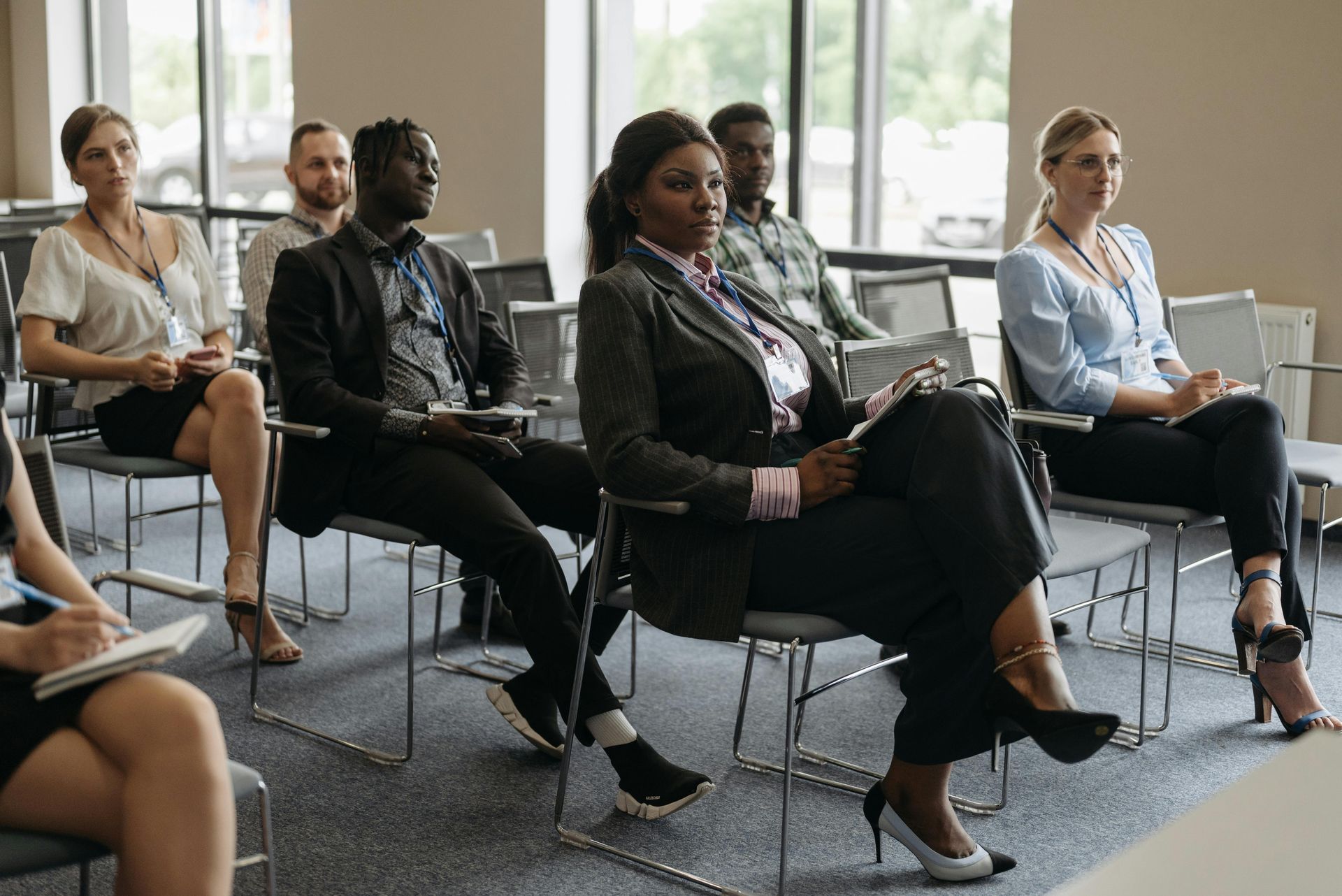 Des personnes assises dans une salle de conférence lumineuse écoutent une réunion ou une présentation.