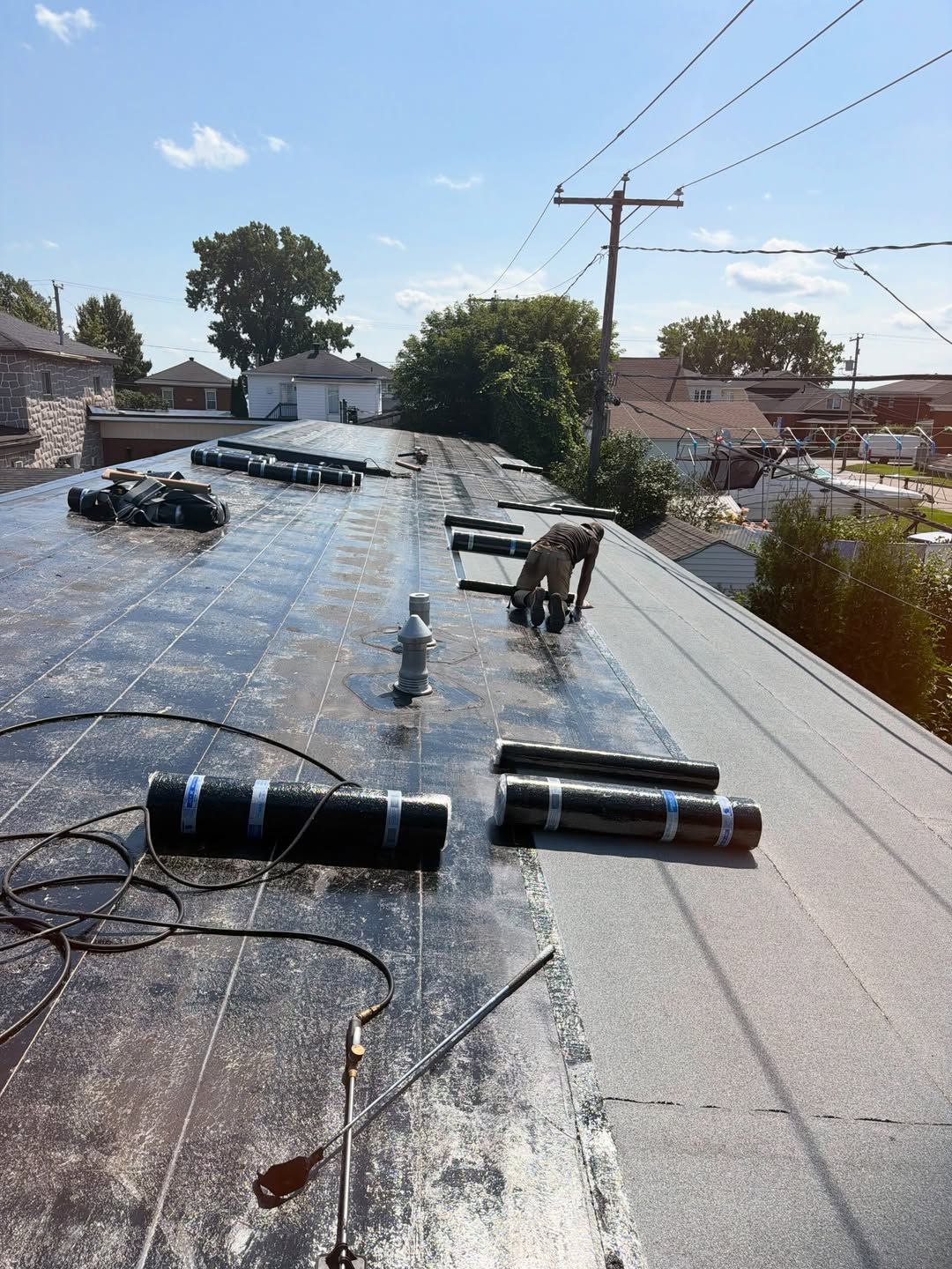 Toit équipé de panneaux solaires et de matériel, en plein soleil, avec des maisons et des arbres en arrière-plan