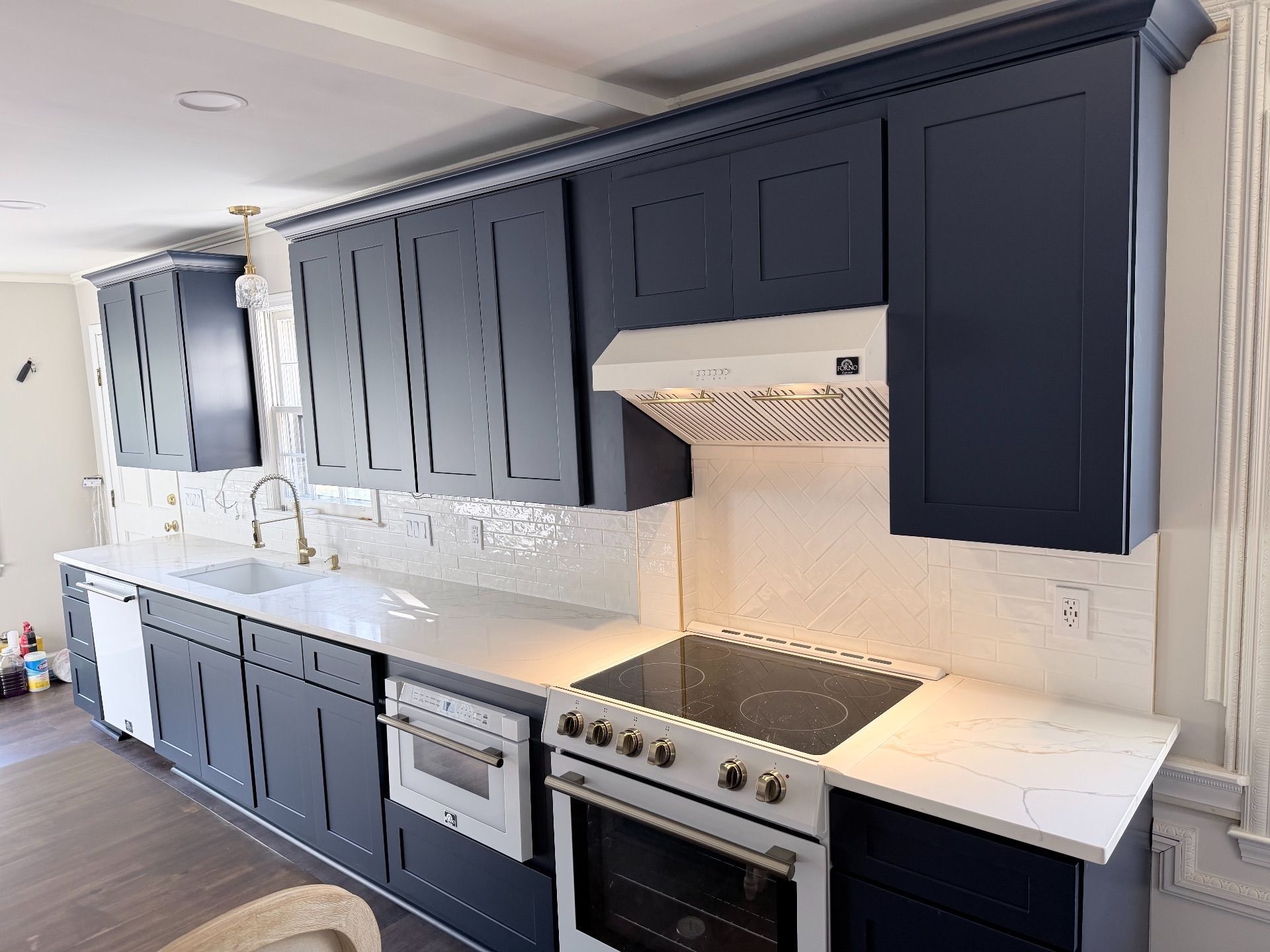 Modern kitchen with navy cabinets, white countertops, stainless appliances, and a tiled backsplash