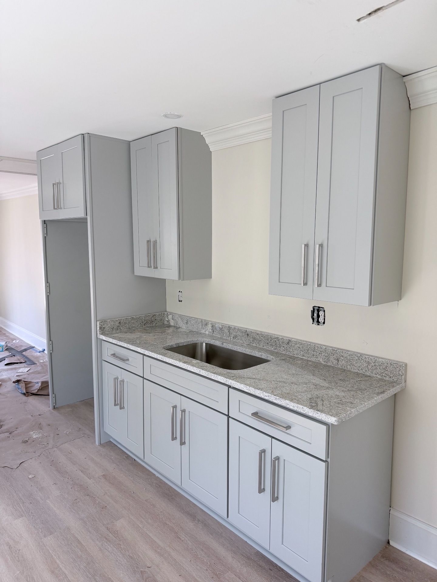 Gray kitchen cabinets and granite countertop in a bright unfinished room