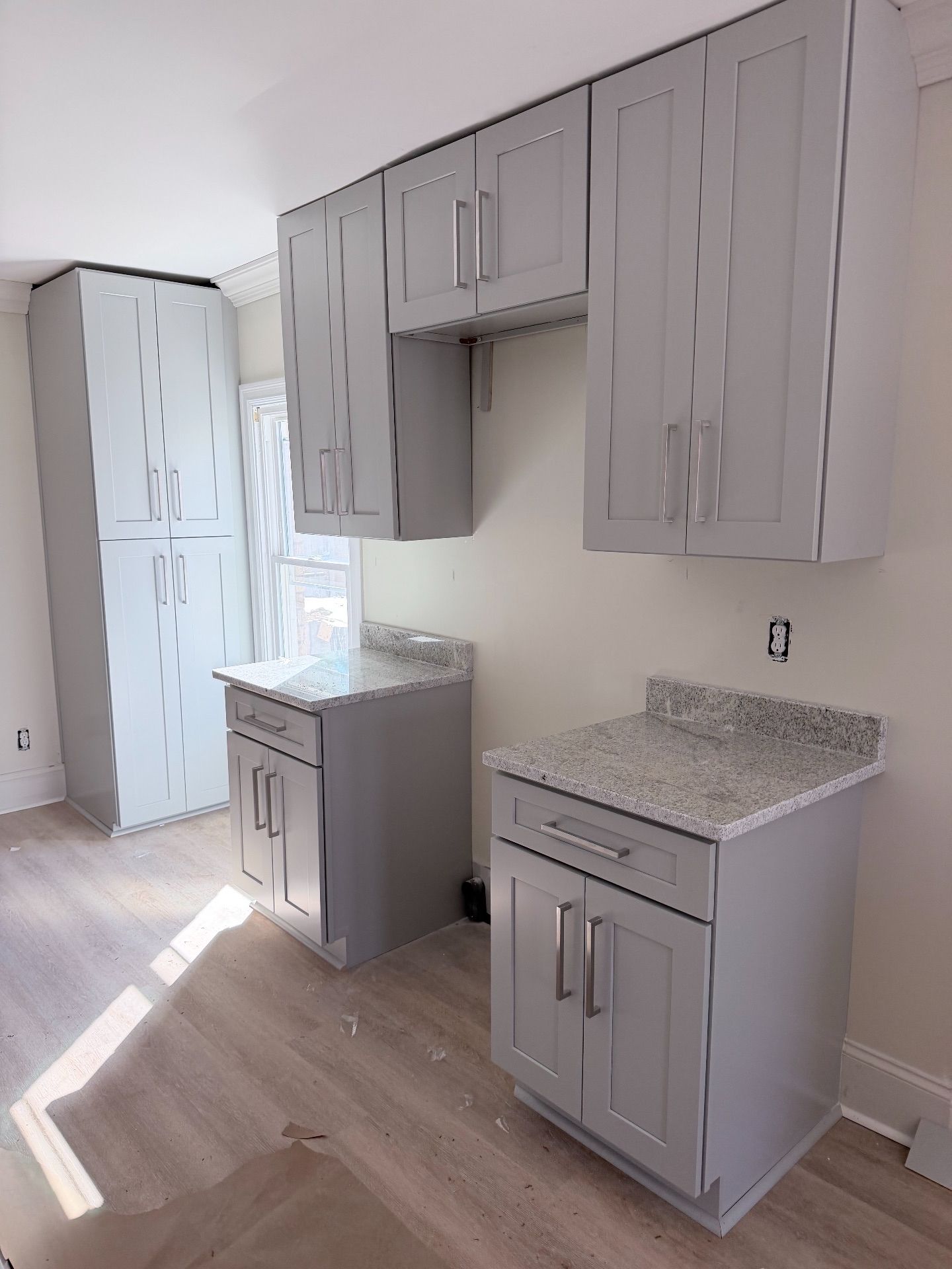 Empty modern kitchen with gray cabinets, white countertops, and wood-look flooring
