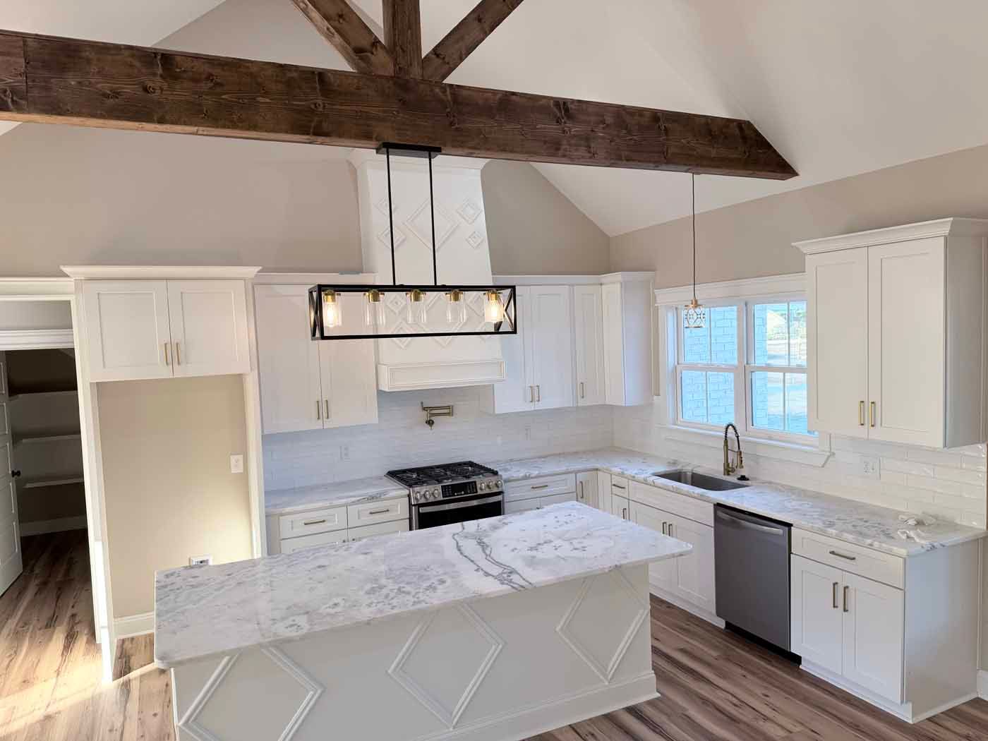 Bright white modern kitchen with marble island, exposed wood beams, and stainless appliances