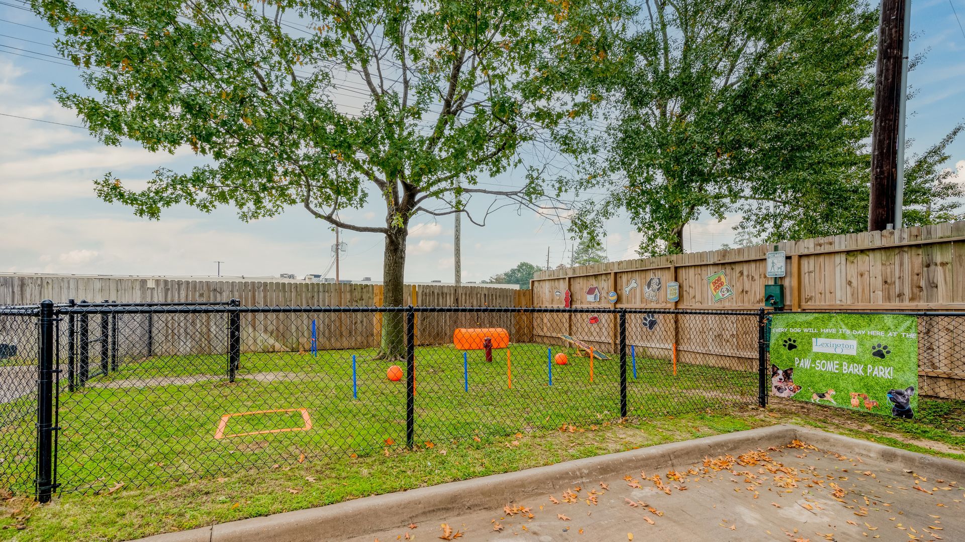 Fenced dog park with agility equipment and green space at The Lexington at Champions Apartments in Northwest Houston, TX.