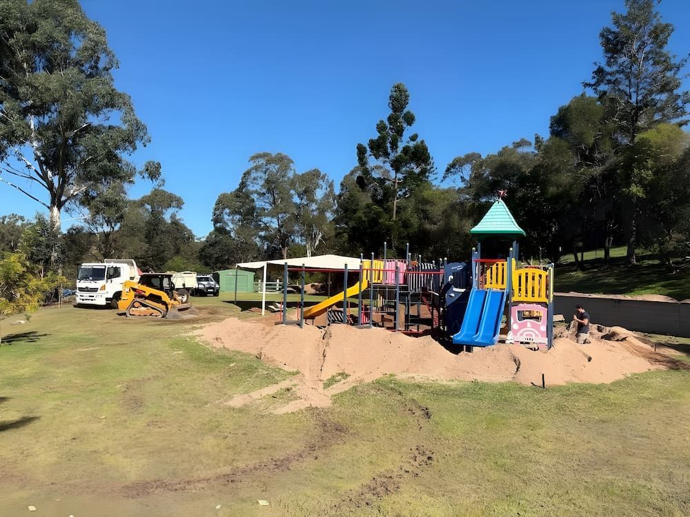 A Bulldozer is parked by a newly built playground in a park — Norcoast Diggers in Ballina, NSW
