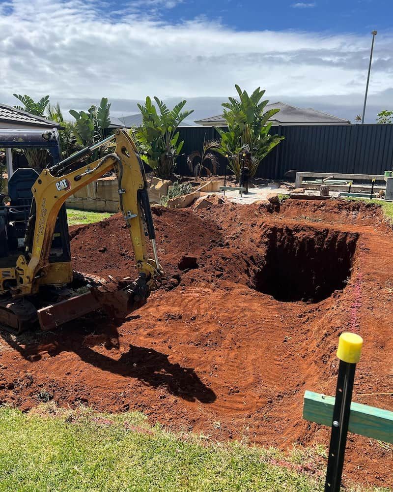 A Yellow Excavator is Digging a Hole in the Ground — Norcoast Diggers in Lismore, NSW