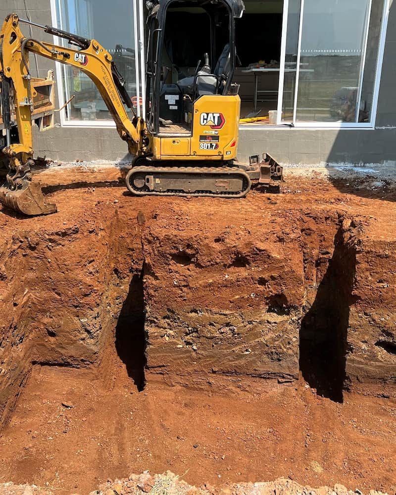 A Yellow Cat Excavator Is Digging a Hole in The Dirt — Norcoast Diggers in Ballina, NSW