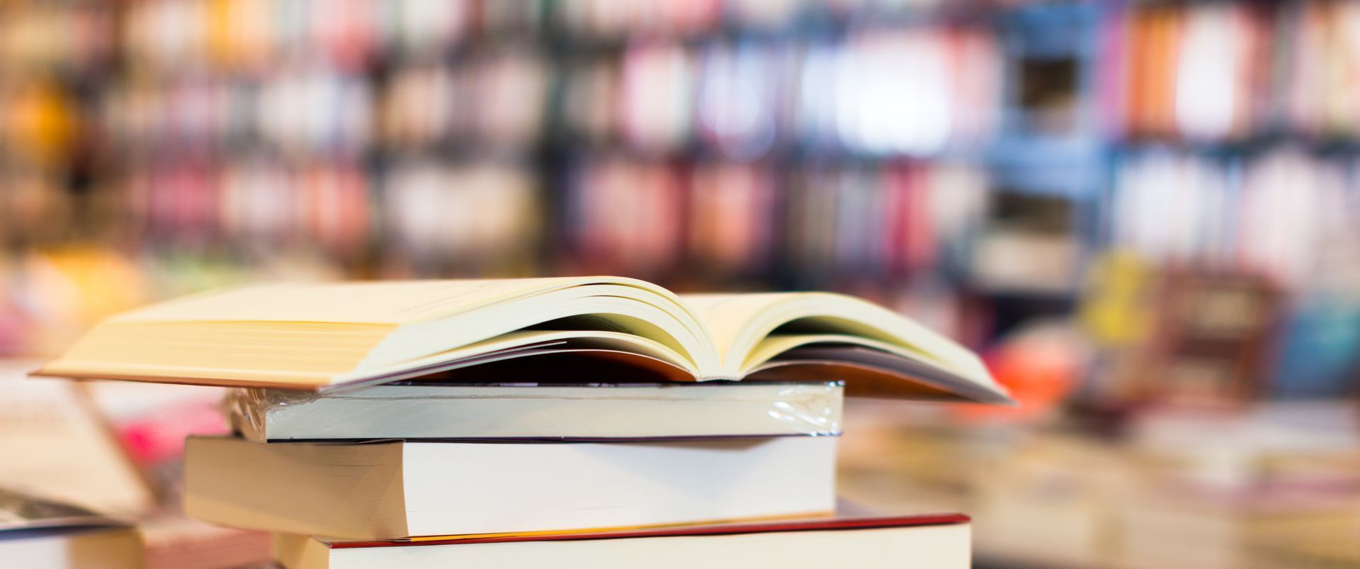 a stack of books with an open book laid out on top.