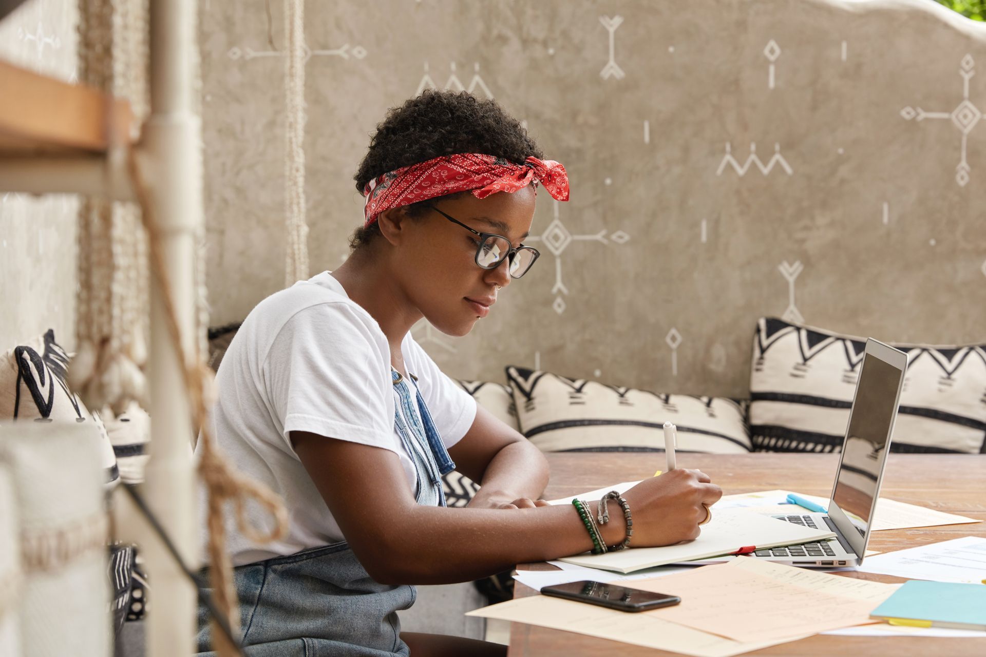 Image of a young woman sitting at a desk writing on a pad of paper.