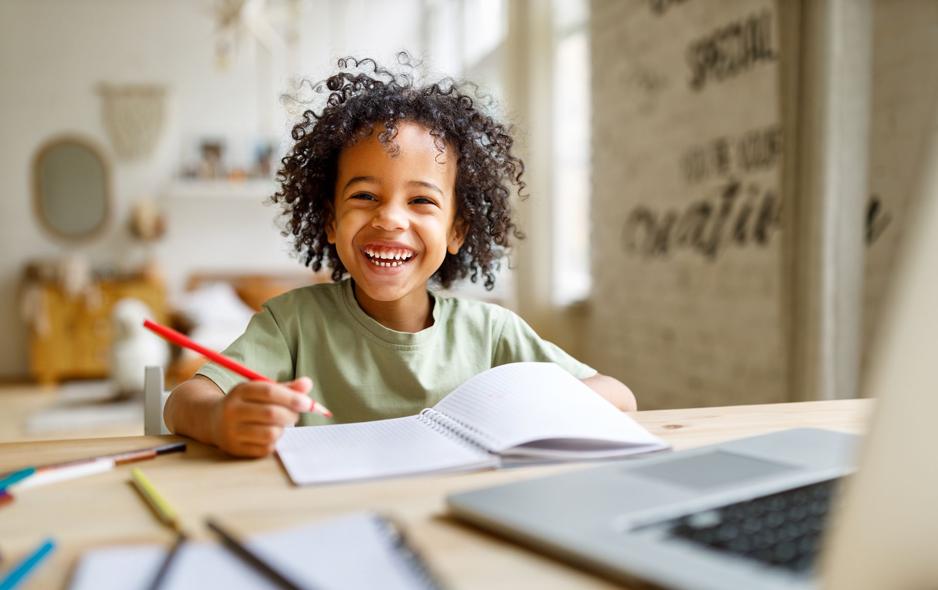 A child sitting at a desk with an open notebook and pencil.