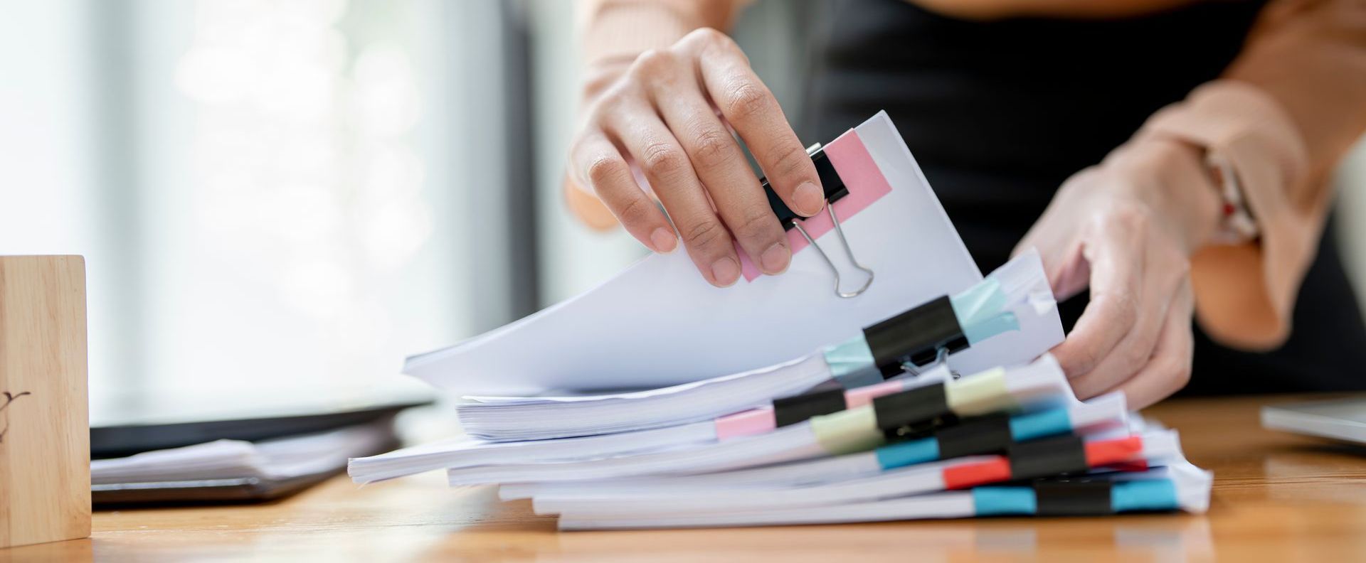 A stack of papers marked with various colors being sorted through.
