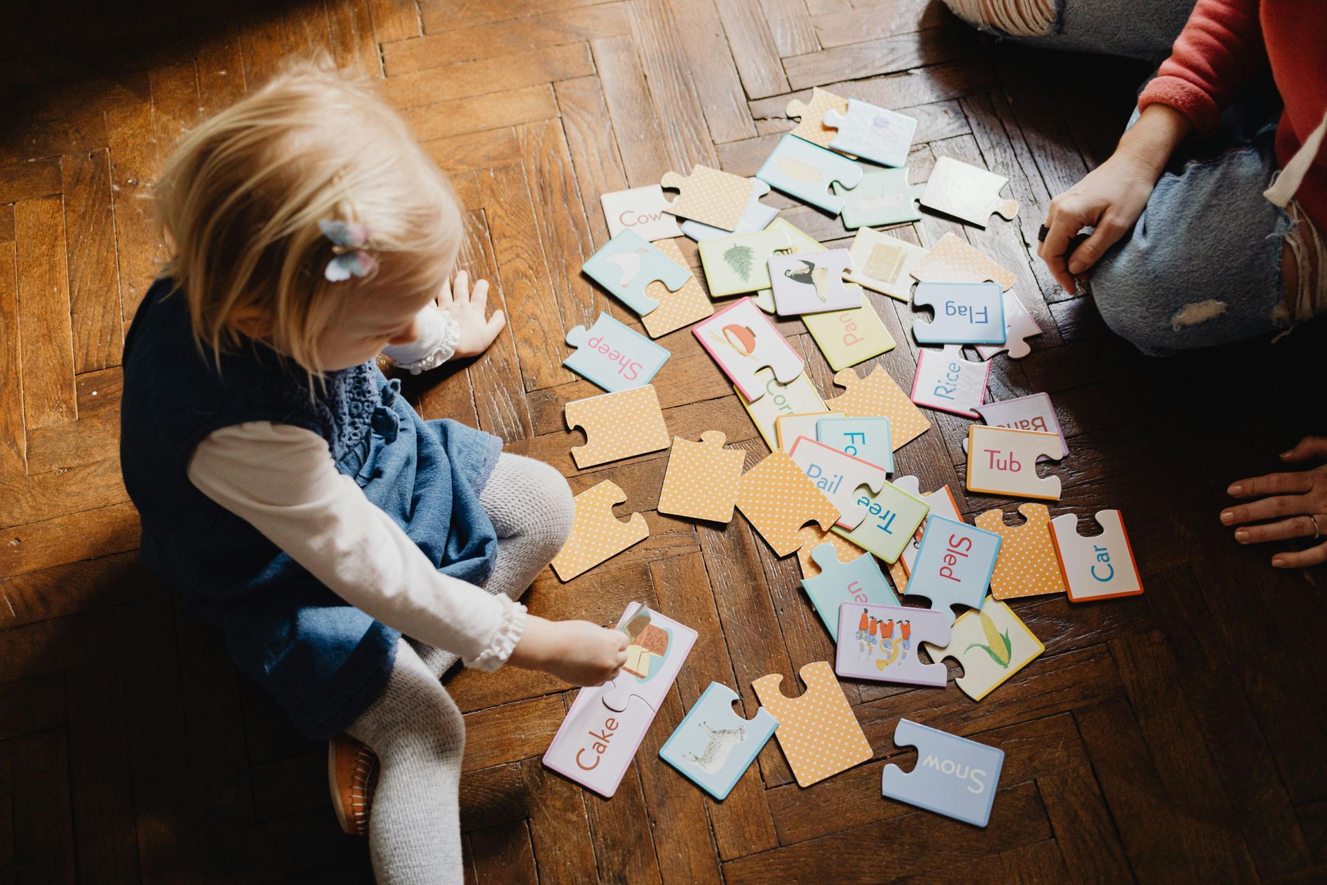 A child sitting on the floor in front of the pieces of a puzzle.