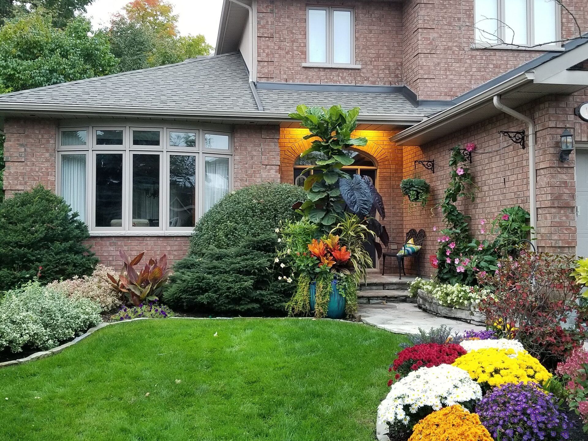 A brick house with a lush green lawn and flowers in front of it