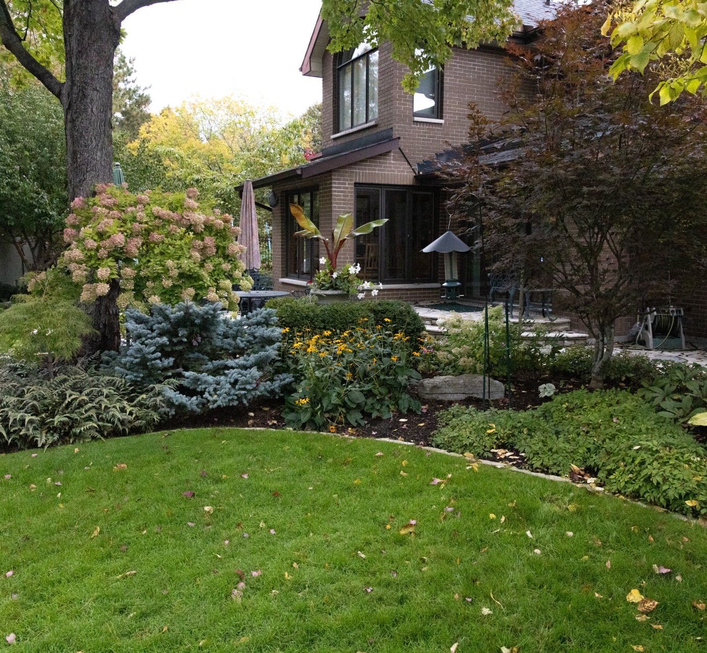 A large brick house with a lush green lawn in front of it.