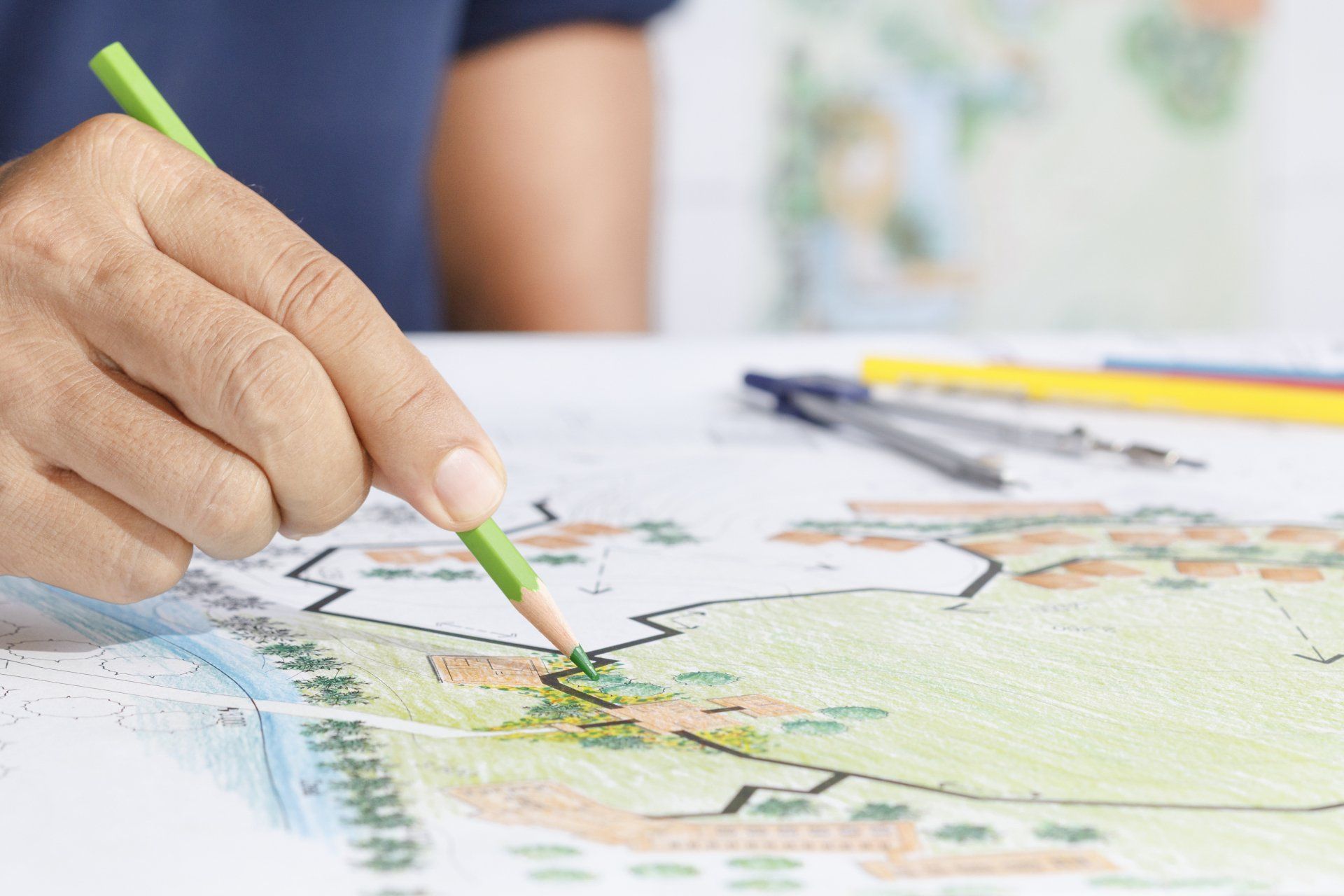 A person is drawing a map with a green pencil.