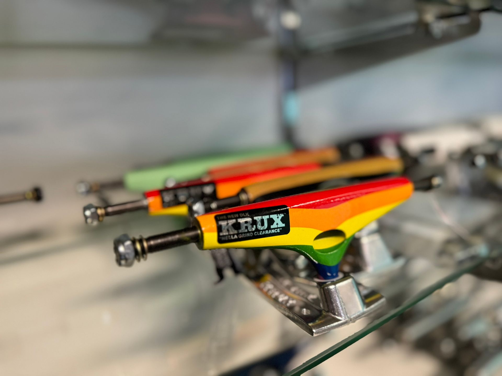 Close-up of colorful skateboards stacked on a glass shelf, with one yellow-red deck in focus.
